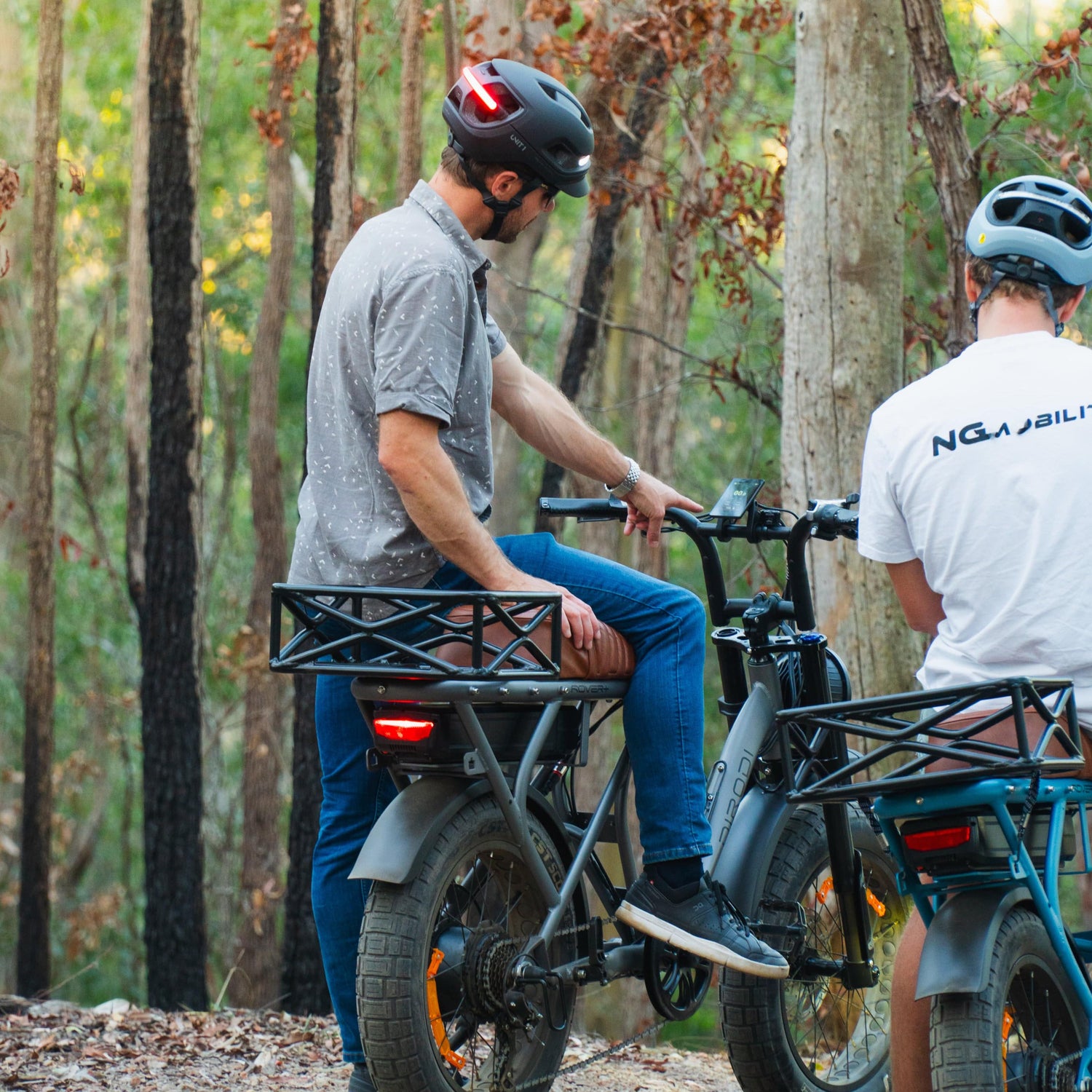 Two riders on NG Mobility e-bikes stopped in forest.