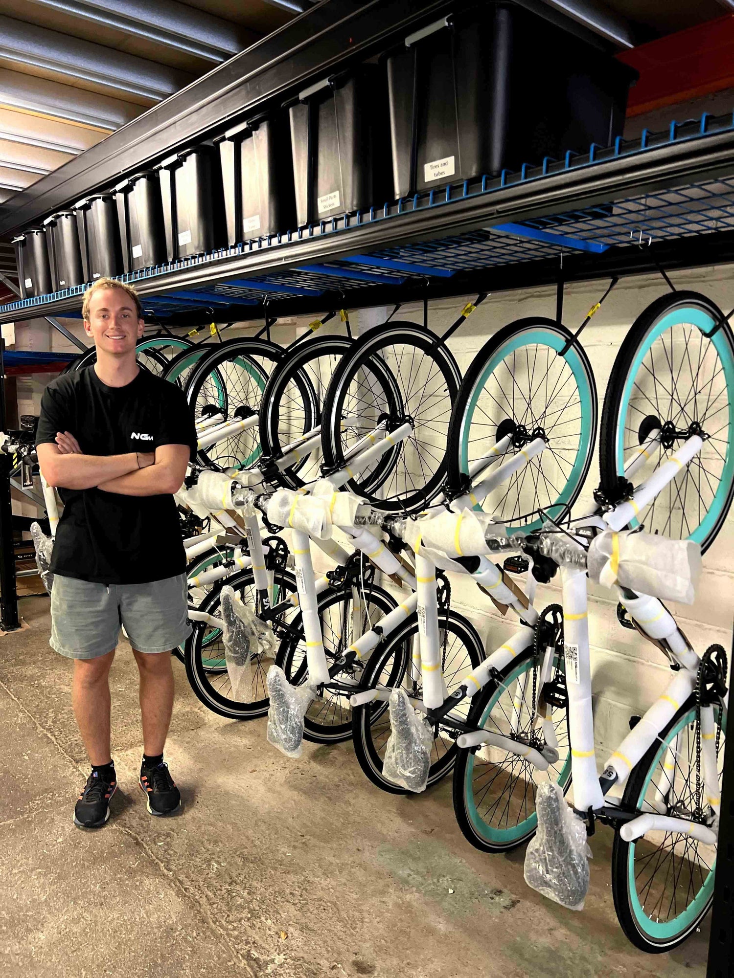 Man standing beside hanging row of packaged Yerka bikes.