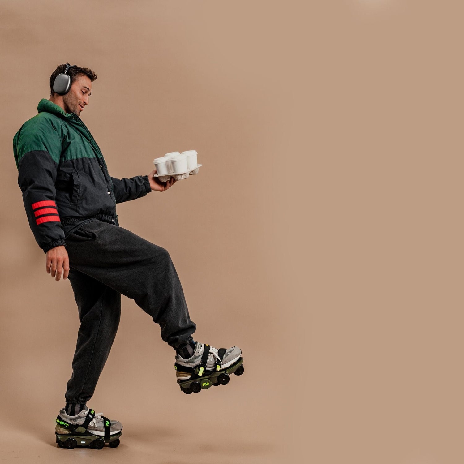 Man wearing electric skates carrying coffee while walking playfully.