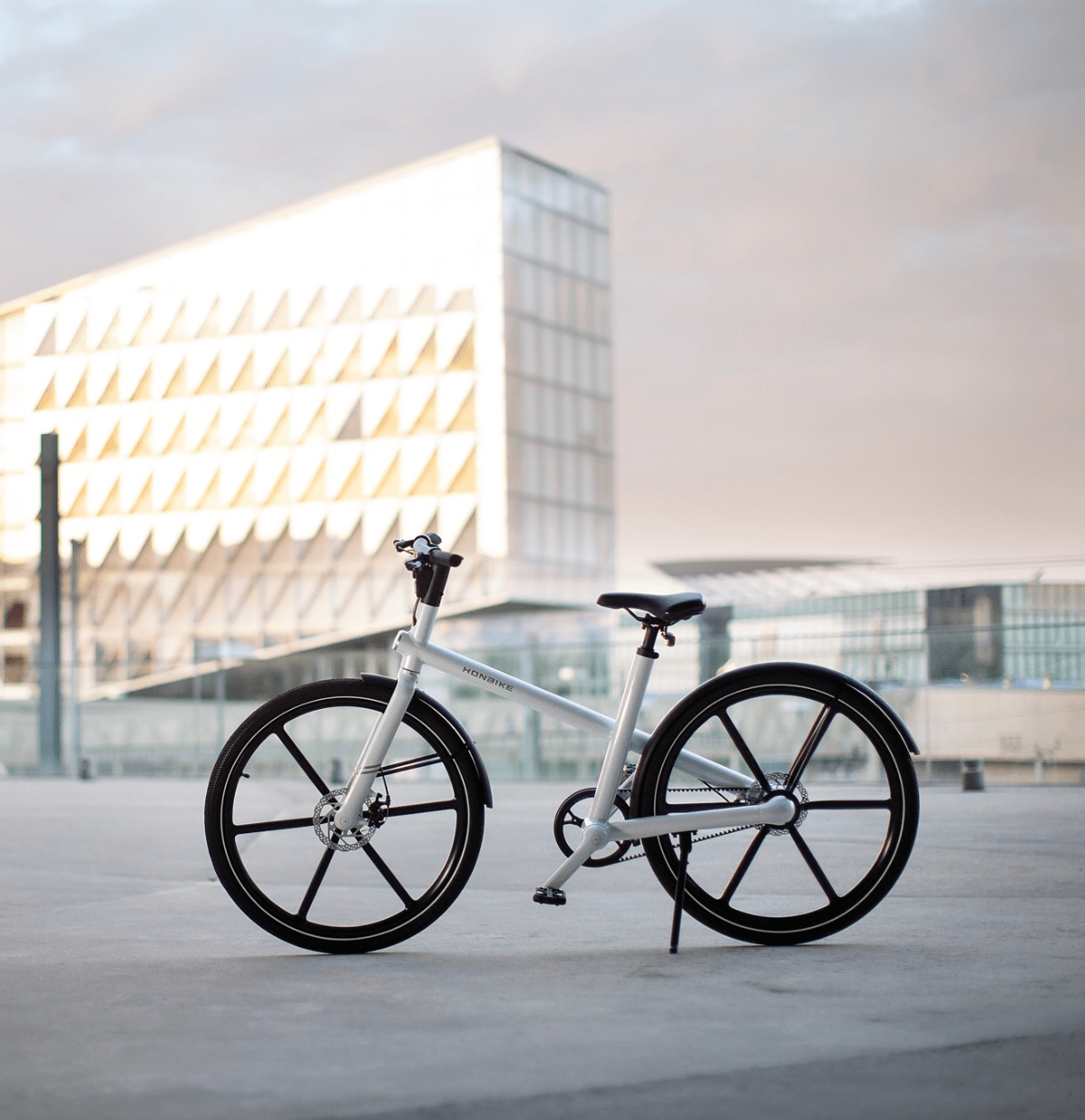 Modern white bicycle parked in front of futuristic building