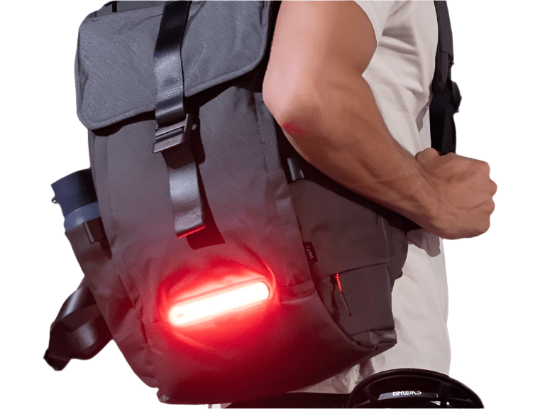 Person wearing backpack with bright red rear safety light attached