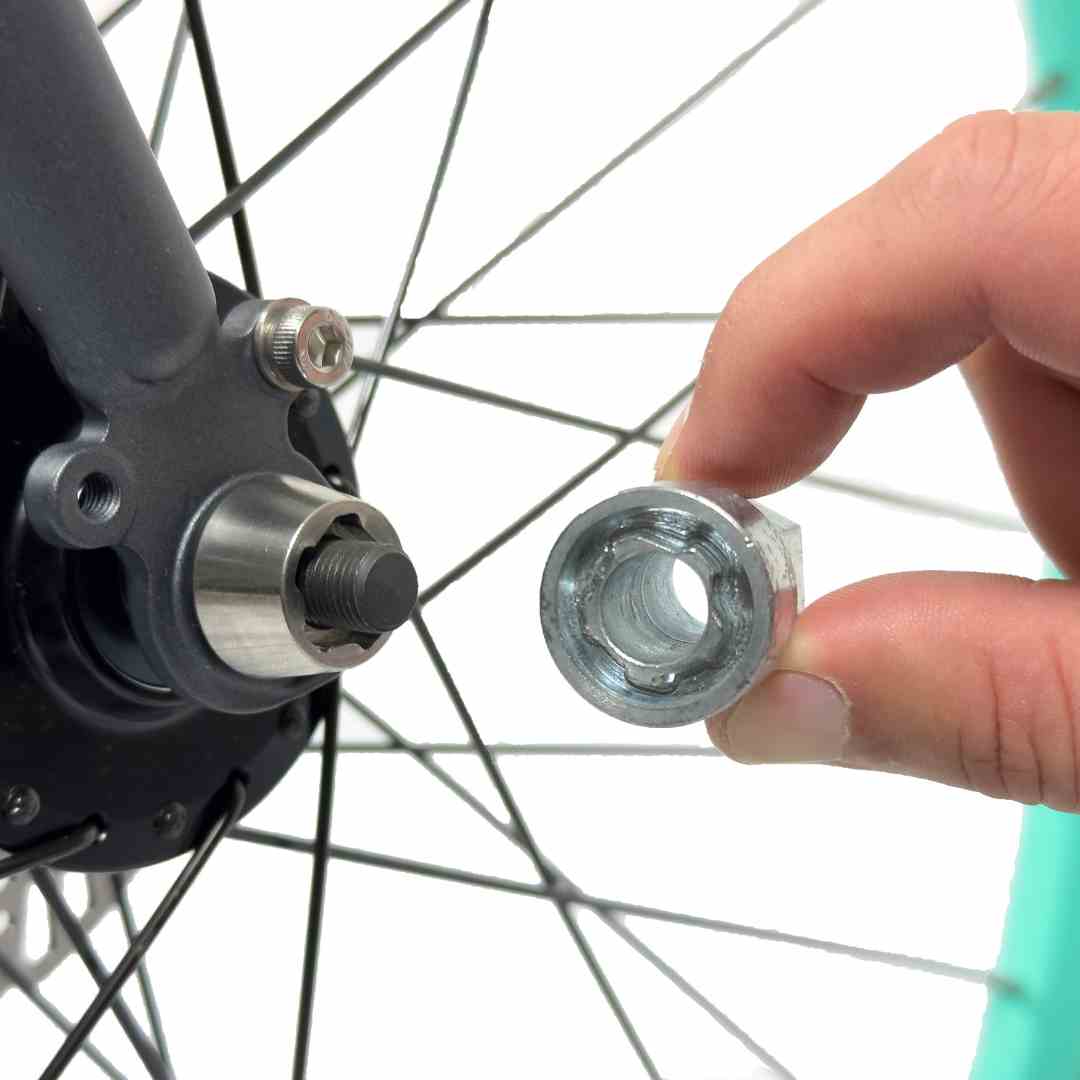 Close-up of hand holding axle nut near bicycle wheel hub