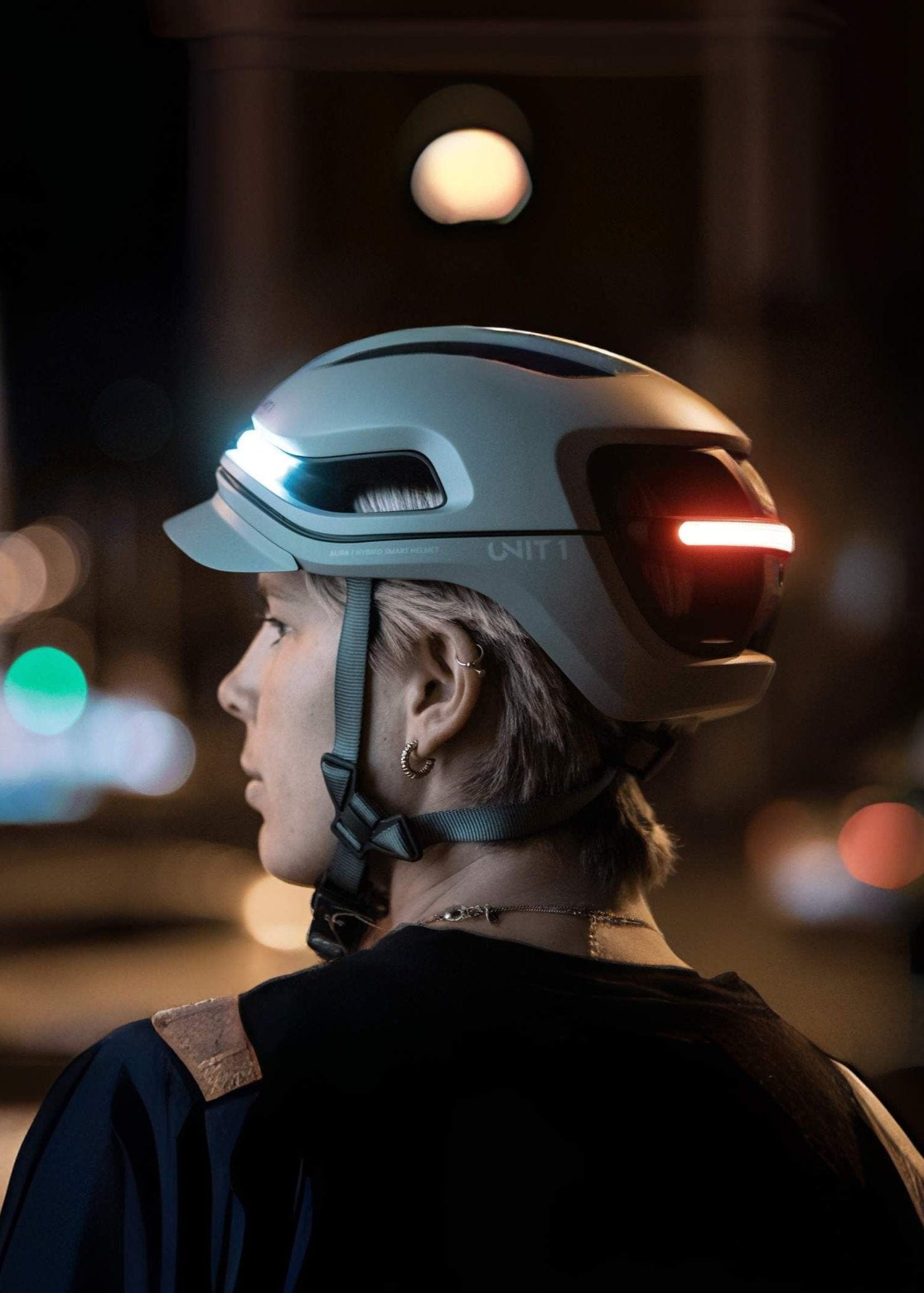 Person wearing UNIT 1 smart helmet with lights at night.