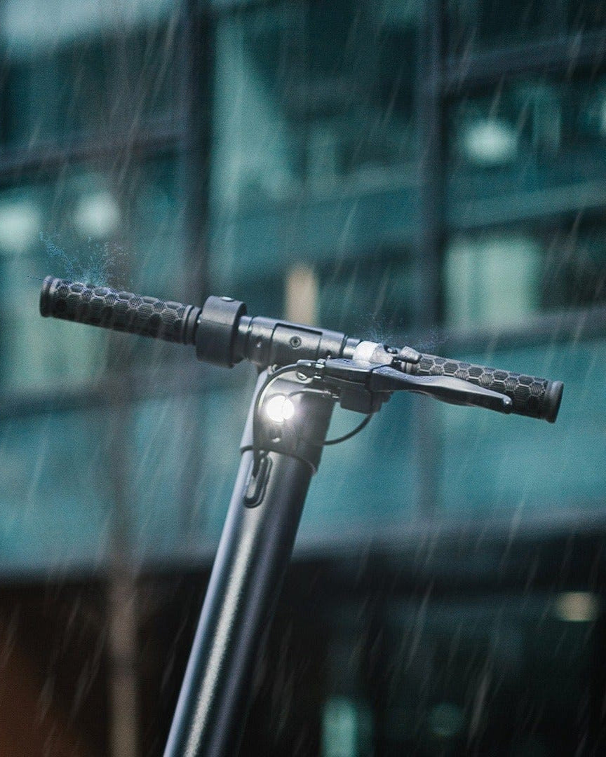Close-up of electric scooter handlebars with light in the rain