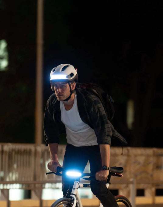 Man cycling at night wearing helmet and bike with bright front lights