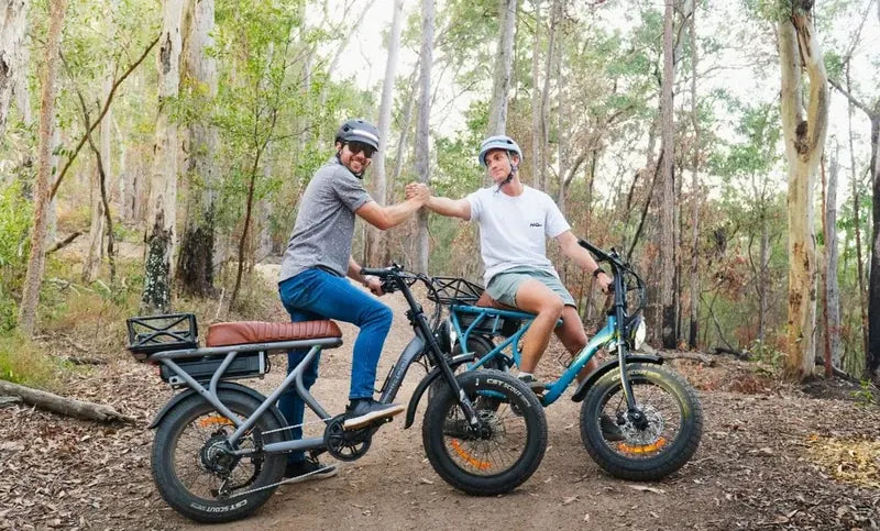 Two riders with DiroDi Rover e-bikes on a wooded trail