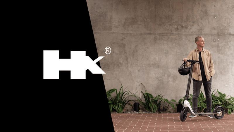 Man standing with HX electric scooter against concrete wall