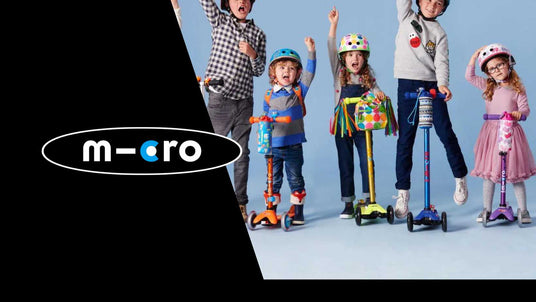 Group of happy kids riding colourful Micro scooters indoors